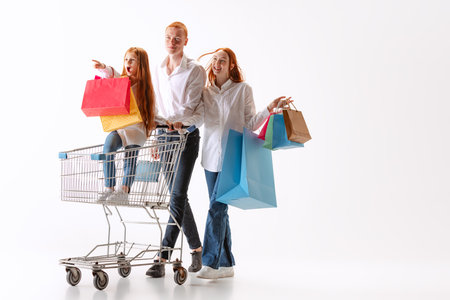 Happy and excited family, young readhaired people walking together after shopping with purchases in hands isolated on white bakground.の写真素材