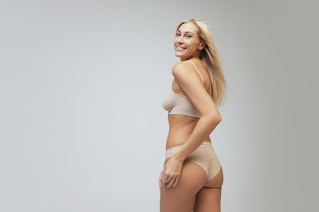Beautiful young woman isolated on light background. Caring for womens health, body treatment, sport and natural beauty concept. Back viewの写真素材