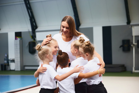 Little girls, beginner gymnastics athletes doing exercises with gymnastics equipment at sports gym, indoors. Concept of studying, achievements, skillsの写真素材