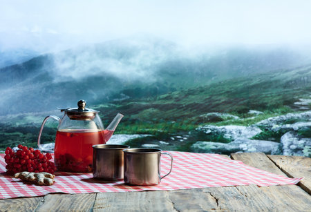 Glass pot with fruit or berries tea, cakes, biscuits on table over winter snow natural landscape background. Design for greeting card, poster for adの写真素材
