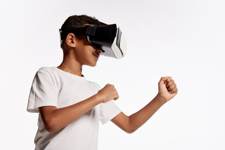 School age boy wearing casual style outfit enjoying 3D technology in virtual reality headset...