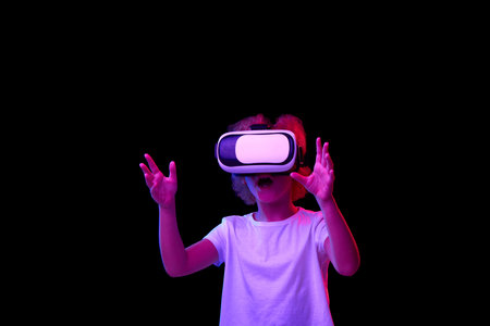 School age girl wearing white t-shirt enjoying 3D technology in virtual reality headset isolated on...