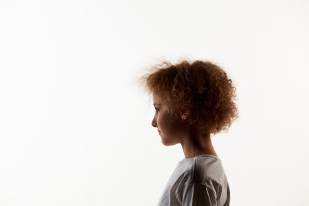 Profile view of little girl, kid in white t-shirt isolated over white studio background. Concept of children emotionsの写真素材