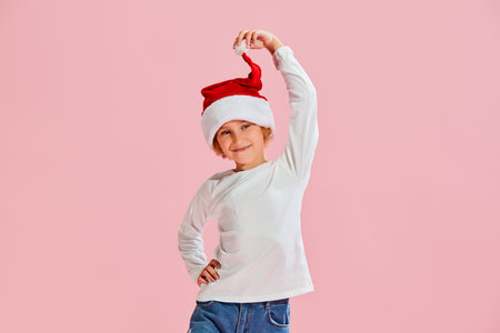 Studio shot of little girl, kid in casual style clothes and warm hat isolated over pink background. Fashion, winter holidays, vacationsの写真素材