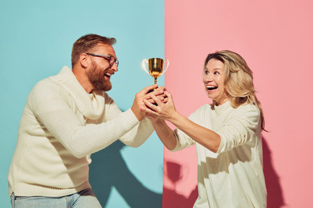 Winner emotions. Excited young people, man and woman, husband and wife spending time together isolated over blue and pink background.の写真素材