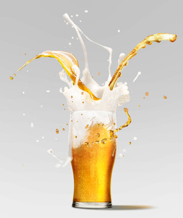 Foam splashes from full glass of frothy light lager beer isolated over light background. Concept of alcohol, oktoberfest, drinks, holidays and festivals.の写真素材