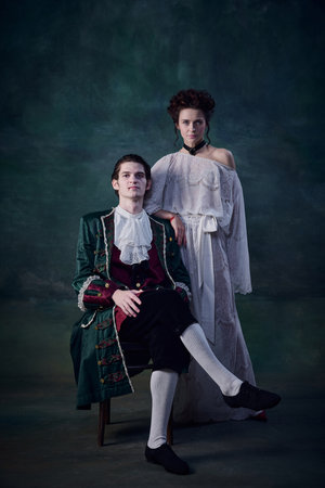 Portrait of legend medieval family, man and woman in image of vampires over dark green background....