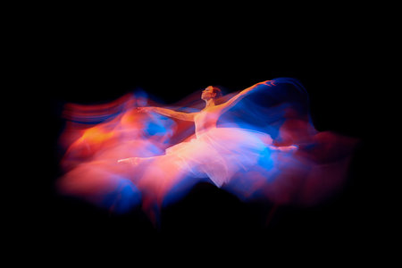 Futurism, fantasy, miracle. Graceful and fragile ballerina in ballet dress jumping isolated over black background in mixed neon light.の写真素材