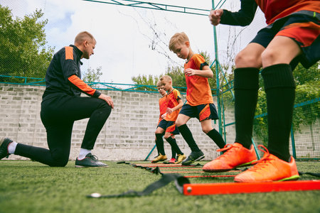 Workout. Junior soccer team training with football coach at sports stadium, outdoors. Concept of sport, competition, studying and achievementsの写真素材