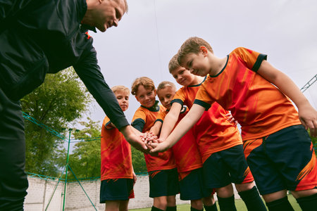 Determined to win. Junior soccer team stacking hands before a match, outdoors. Concept of sport, competition, studying and achievementsの写真素材