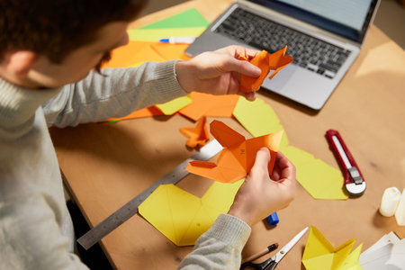 Making paper animal. Young man holds a master class on origami and recording vlog at home studio. Hobbies and leisure activities. Remote training, online classesの写真素材