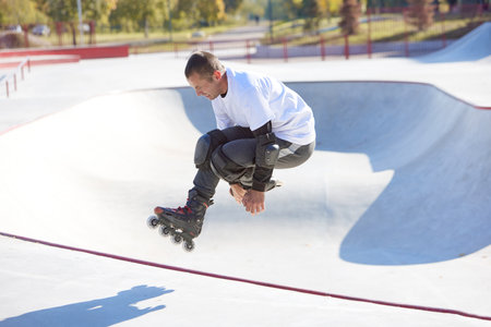 Energetic man on roller skates in motion at modern roller skate park. Roller skater doing dangerous...