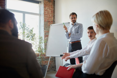 Discussion of a new project. Young men and women. coworkers at business meeting at office open space, indoors. Finance, training, brainstorming, work.の写真素材