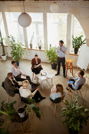 Aerial view of young people talking, working, discussing problems and ideas with colleagues,...