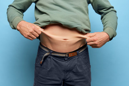 Cropped image of man showing his belly, abdomen. Close Up part of mans body. Concept of dieting, sport, fitness, healthy lifestyle, body positiveの写真素材