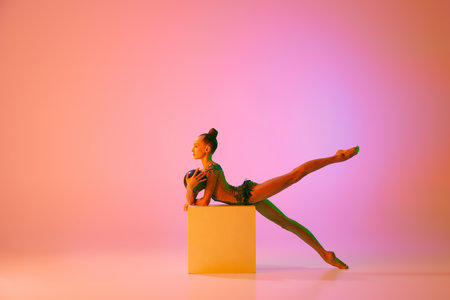 Beautiful and flexible graceful athlete rhythmic gymnastic artist dancing, doing stretch exercises isolated on colorful background in neon. Beauty, art, sportの写真素材