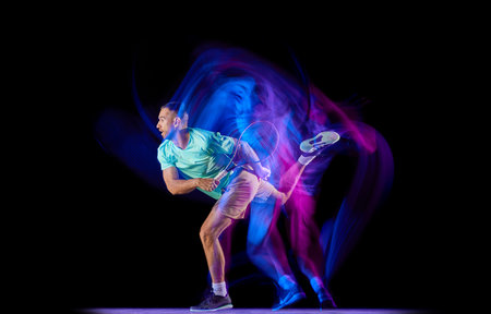 Studio shot of professional tennis player playing tennis isolated over dark background in mixed neon light. Concept of motion, speed, professional sport.の写真素材