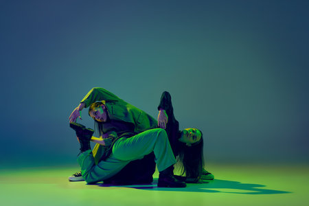 Young stylish flexible girls in modern attires dancing contemp style dance isolated over gradient...