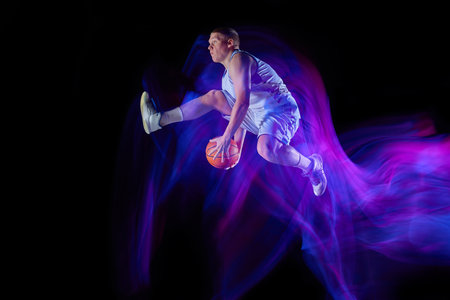 Studio shot of young active athlete, male basketball player in sports uniform in motion and action...