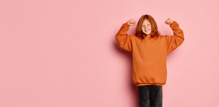 Flyer with excited little girl, emotional kid with charming freckles standing with raising hands up isolated over pink background. Concept of children emotions, sport, active lifestyleの写真素材