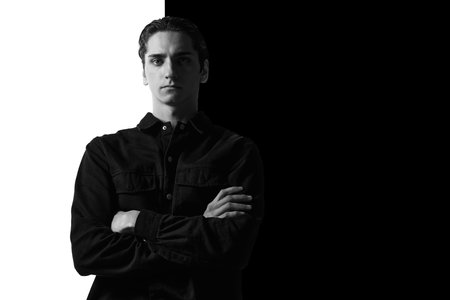 Black and white portrait of young man in casual shirt posing, seriously, attentively looking at...