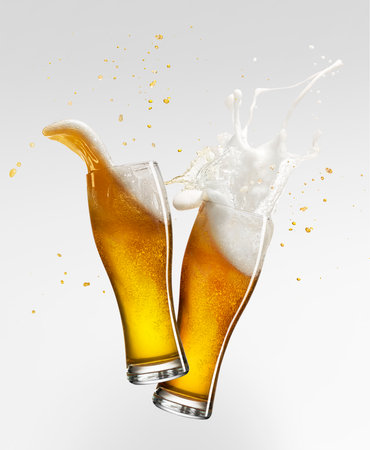 Foam splashes. Two glasses with lager foamy beer isolated over grey background. Concept of alcohol, oktoberfest, drinksの写真素材
