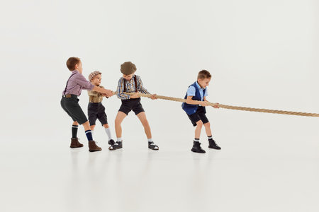 Motivation to win. Group of little boys, children playing together, pulling the rope over grey studio background. Concept of game, childhood, friendshipの写真素材
