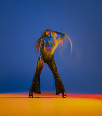 Sensual young girl dancing heels dance in stylish clothes over blue background in neon with mixed lights. Concept of modern dance styleの素材 [FY310197228951]