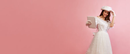 Modern devices. Video call. Portrait of beautiful lady in white vintage dress posing with tablet over pink background. Concept of 19th century, fashion, comparison of erasの写真素材