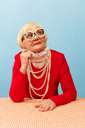Stylish accessories. Beautiful old woman, grandmother in stylish red dress and pearl necklace posing...