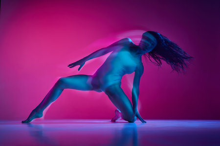 Freestyle. Sensuality. Young woman dancing in bodysuit over gradient pink studio background in neon with mixed lights. Concept of dance aesthetics, artの写真素材