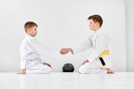 Shaking hands after fight. Boys, children in white kimono, future judo, jiu-jitsu athletes on training sessionの写真素材