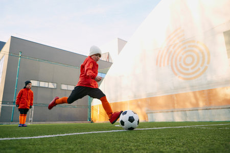In motion. Boy, child, playing football, training on sports field outdoor. Running with ball,...