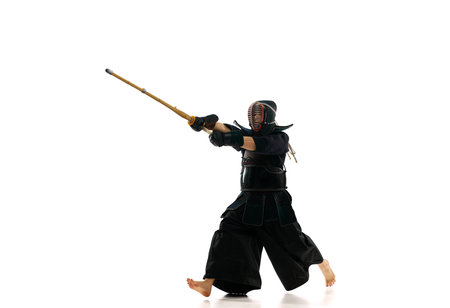 Man, professional kendo athlete in motion, in uniform training with bamboo sword, shinai against...