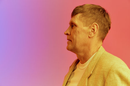 Side view. Portrait of mature, middle-aged man in jacket posing over gradient pink purple background...