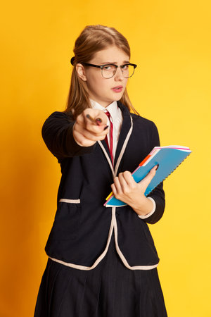 Time to study. Portrait of beautiful young girl, student in uniform with notes pointing with pencil...
