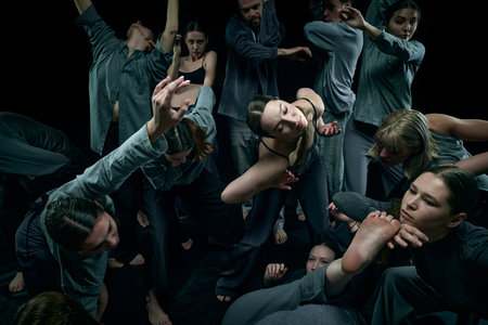 Chaotic movements. Group of different young people dancing against black studio background. Expression. Concept of contemporary danceの写真素材