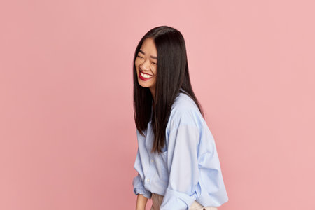 Portrait of young beautiful happy girl in casual clothes posing, smiling against pink studio background. Concept of emotionsの写真素材