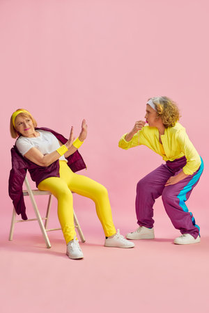 Competition. Two elderly sportive women in colorful uniform training, posing against pink studio background. Concept of sport and healthの写真素材