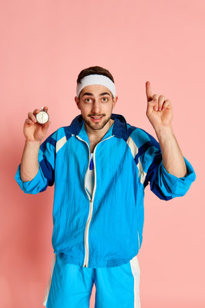 Competition. Portrait of fitness trainer, coach in blue uniform posing with whistle and taimer against pink studio background. Concept of sportive lifestyleの写真素材