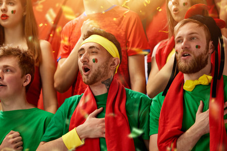 Sport fans emotionally cheering up favourite football, soccer team of portugal at stadium during game, singing anthemの写真素材