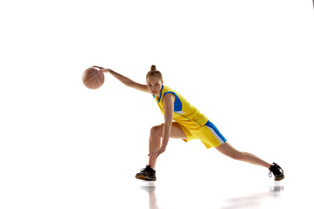Young girl, concentrated basketball player in motion, training, dribbling ball against white studio background. Concept of professional sportの写真素材