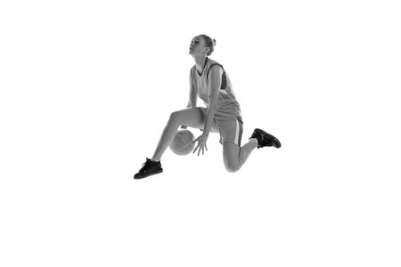 Black and white image of young athletic girl playing, training basketball against white studio background. Concept of professional sportの写真素材