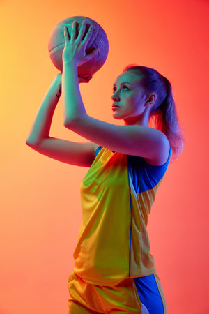 Young concentrated girl, female basketball player in uniform, posing with ball l against white studio background. Concept of professional sportの写真素材