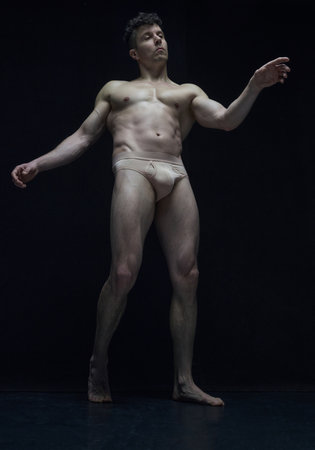 Bottom view portrait of handsome mature man in underwear, posing shirtless against black studio background. Like antique sculpture.の写真素材