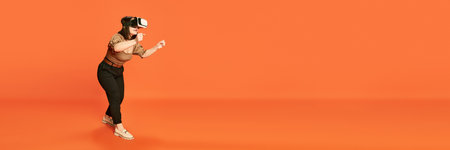 Portrait of young girl wearing VR glases and playin g online vide games against orange studio background. Drivingの写真素材