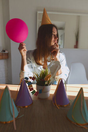 Portrait of young girl in casual clothes getting ready to celebrate birthday. Woman standing at home on daytime with sunlightの写真素材