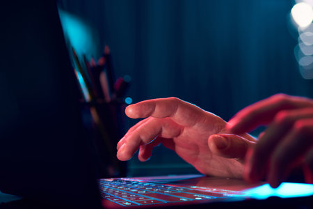 Businessman working remotely, typing on laptop keyboard over neon lights. Working with online projectsの写真素材