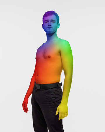 Portrait of young man posing in pants, shirtless with body colored in rainbow colors over white background. Lgbt supporterの写真素材