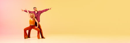 Emotional, beautiful man and woman in vintage clothes dancing retro dance against gradient pink...